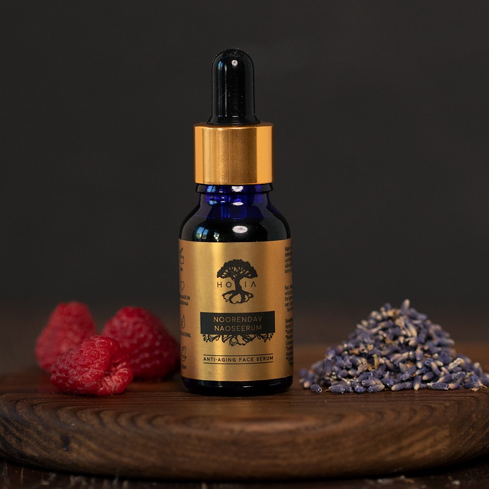 1. HOIA homespa Anti-Aging Face Serum in blue glass bottle with gold label, surrounded by raspberries and lavender, lifestyle setting