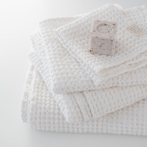 2. Stack of white honeycomb waffle towels with soap bars, highlighting texture and softness