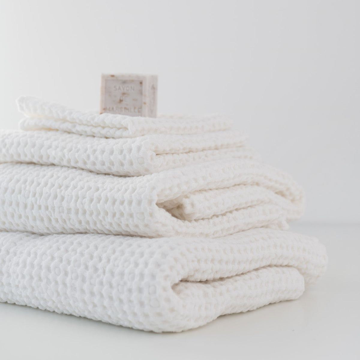 2. Stack of white honeycomb waffle towels with soap bar, showcasing texture and volume