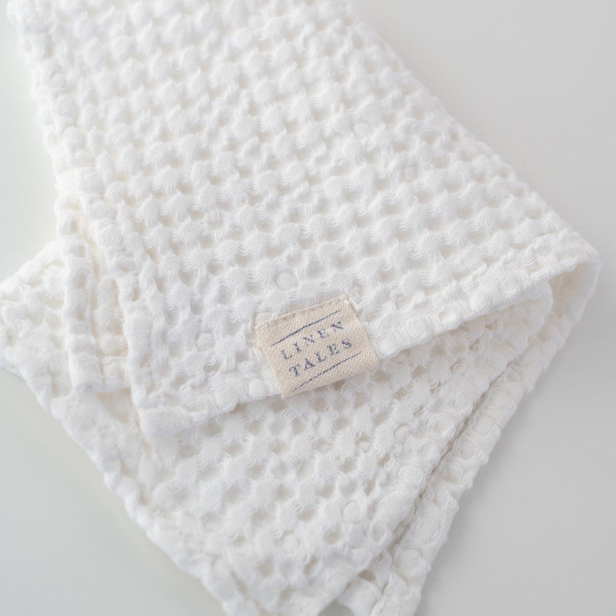 3. Close-up of Linen Tales label on white honeycomb waffle towel, highlighting brand detail