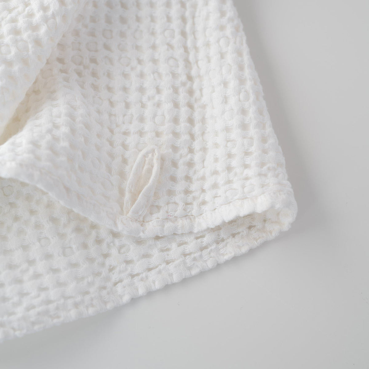 3. Close-up of white honeycomb waffle towel corner with hanging loop detail
