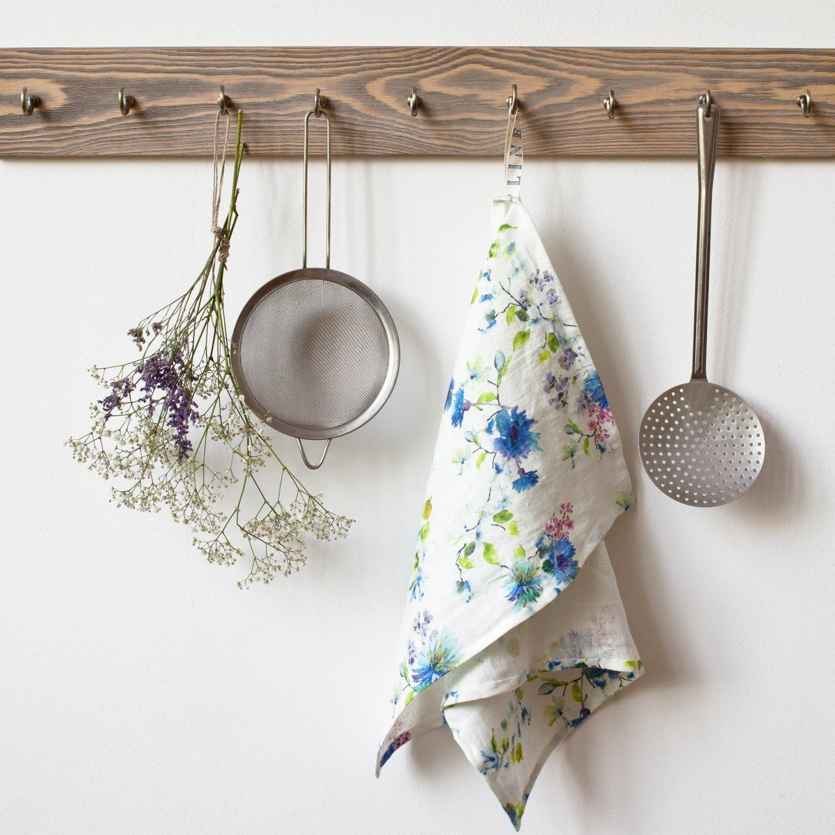 1. Floral print linen kitchen towel hanging on wooden rack with kitchen utensils and dried flowers