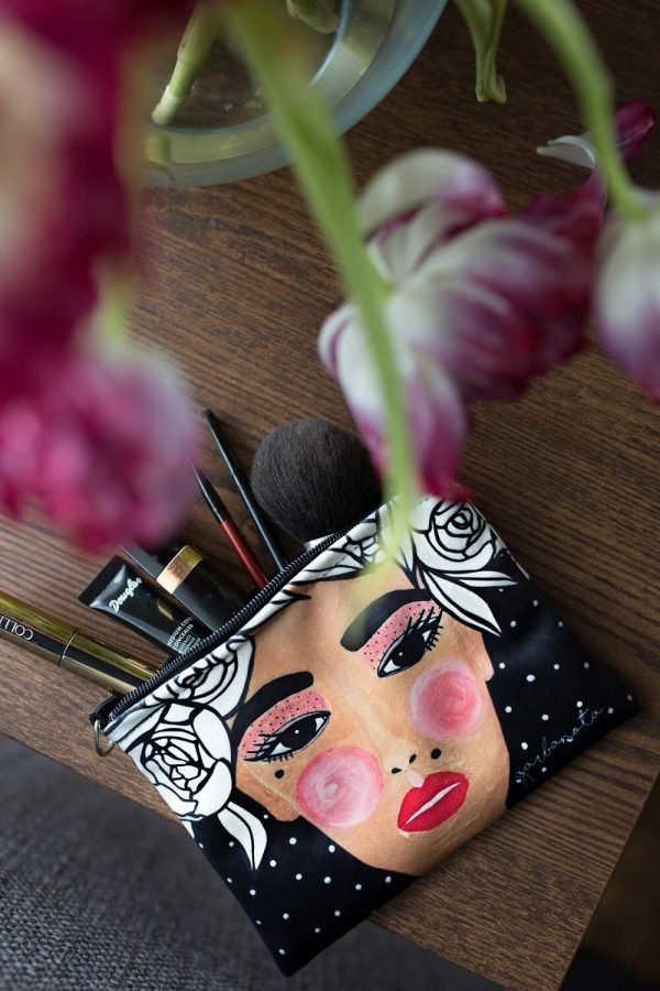 3. Garbanota YOKO makeup bag in black with face illustration, filled with makeup brushes and products