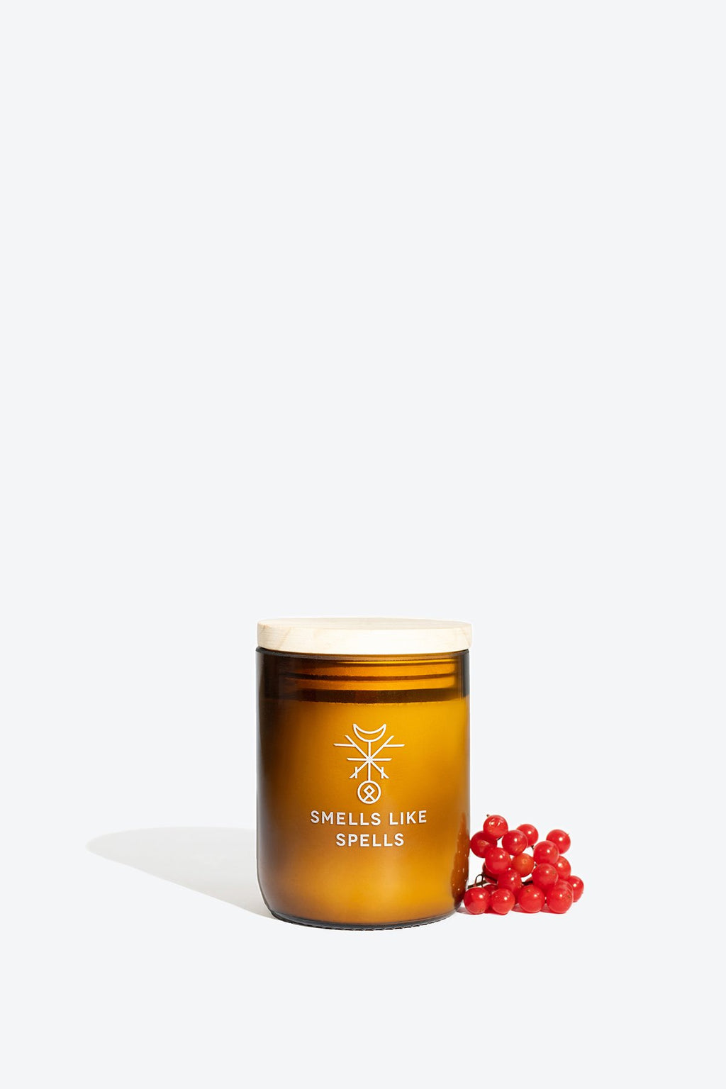 2. Smells Like Spells Scented Candle BRAGI in amber glass jar with wooden lid, styled with red berries