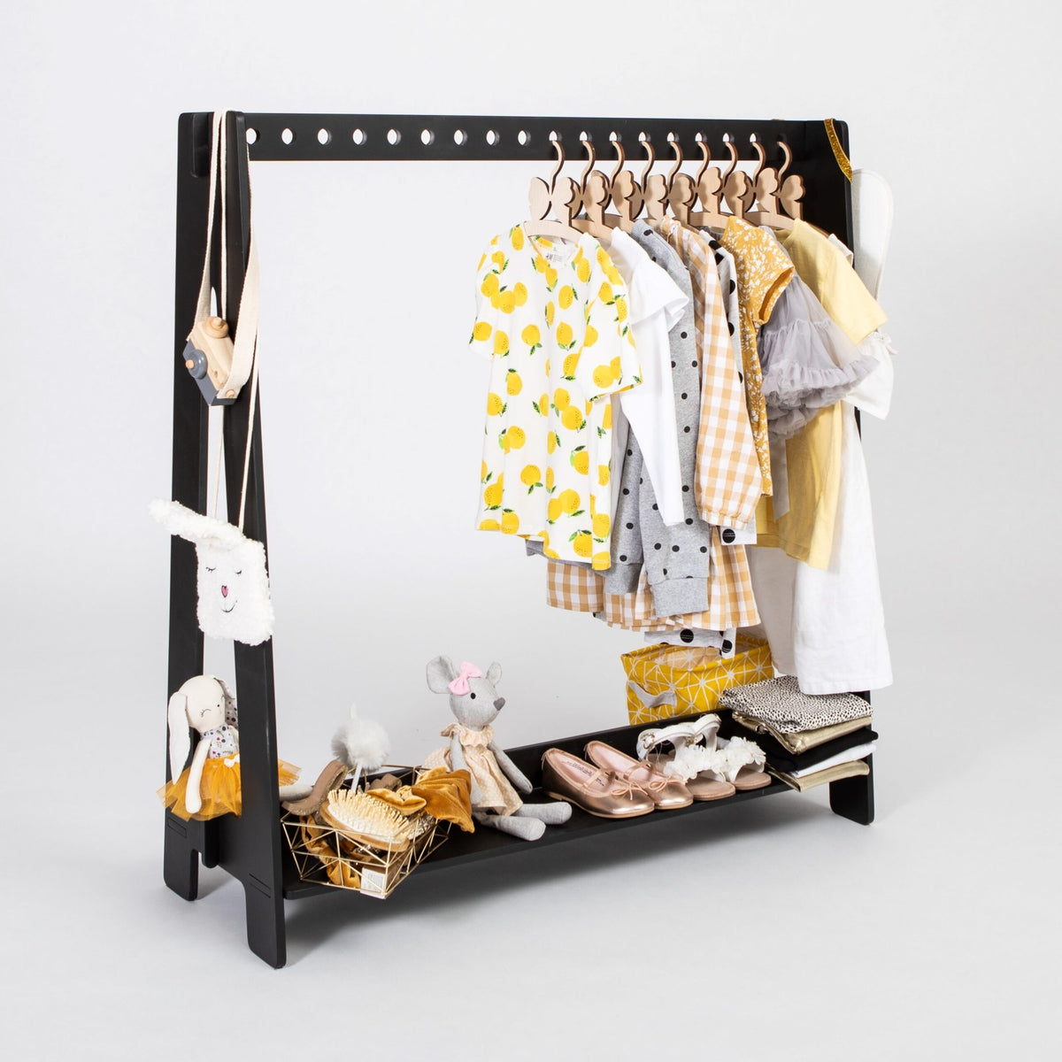 15. Black toddler clothing rack with yellow and patterned clothes, shoes, and toys