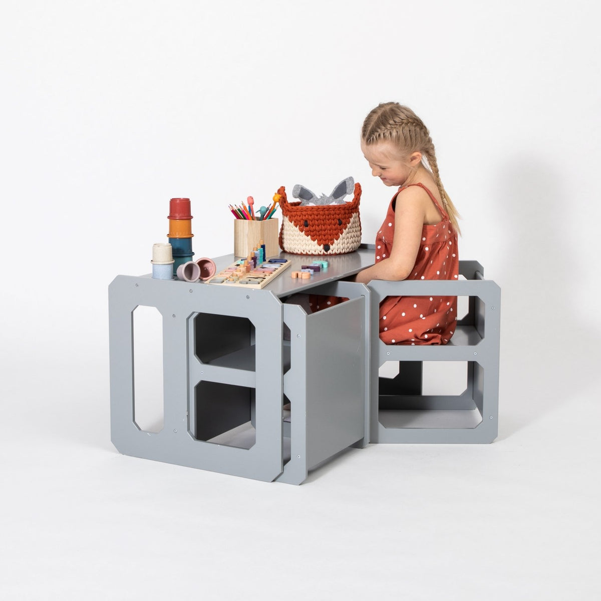 1. Girl in red dress using grey Montessori weaning table and chair set for crafts on white background