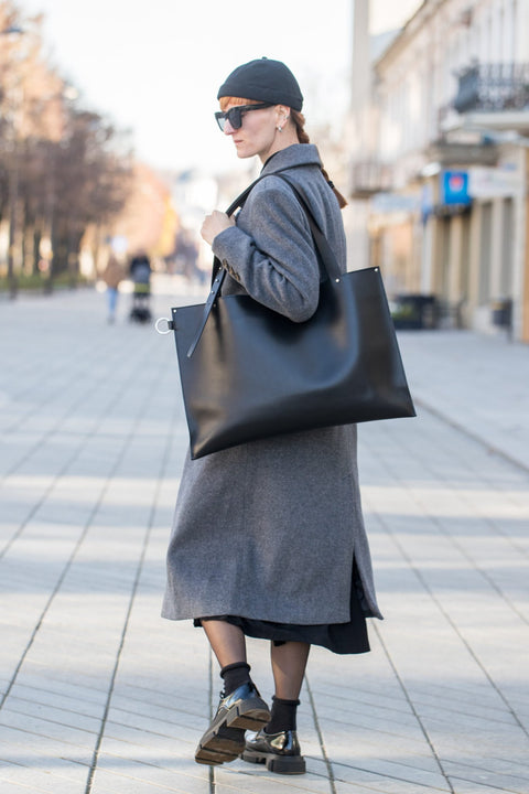 3. Woman with PYKOK Adele black leather handbag, walking in city street, showcasing bag's size and style