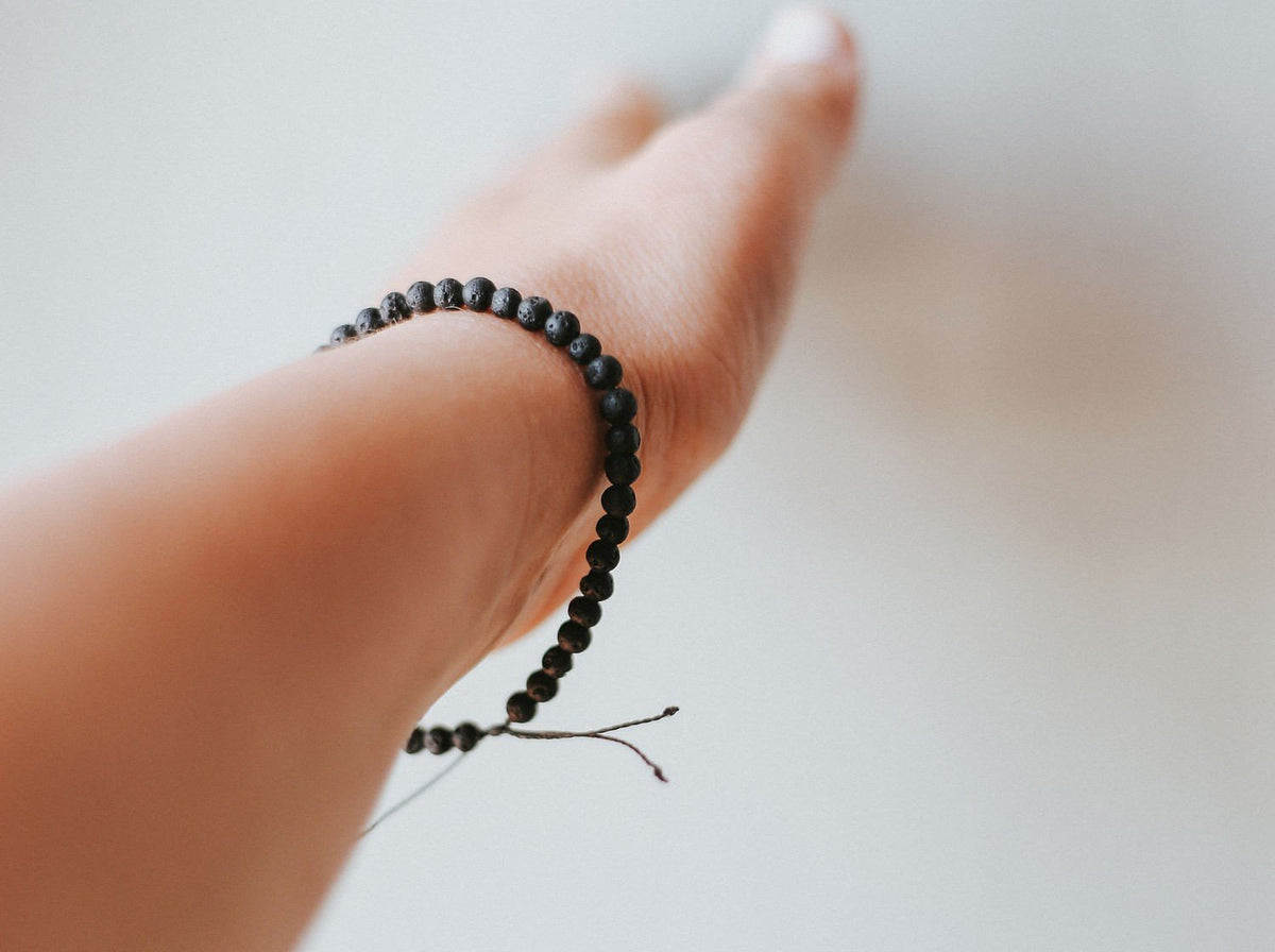 1. Women's adjustable 4mm minimalist lava stone bracelet by Canary Lava, worn on wrist, showcasing volcanic beads and black kevlar string