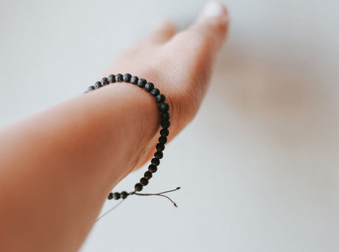 1. Women's adjustable 4mm minimalist lava stone bracelet by Canary Lava, worn on wrist, showcasing volcanic beads and black kevlar string