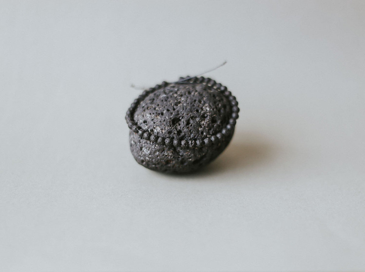 4. Close-up of Canary Lava's lava stone bracelet wrapped around a volcanic rock, emphasizing texture and craftsmanship
