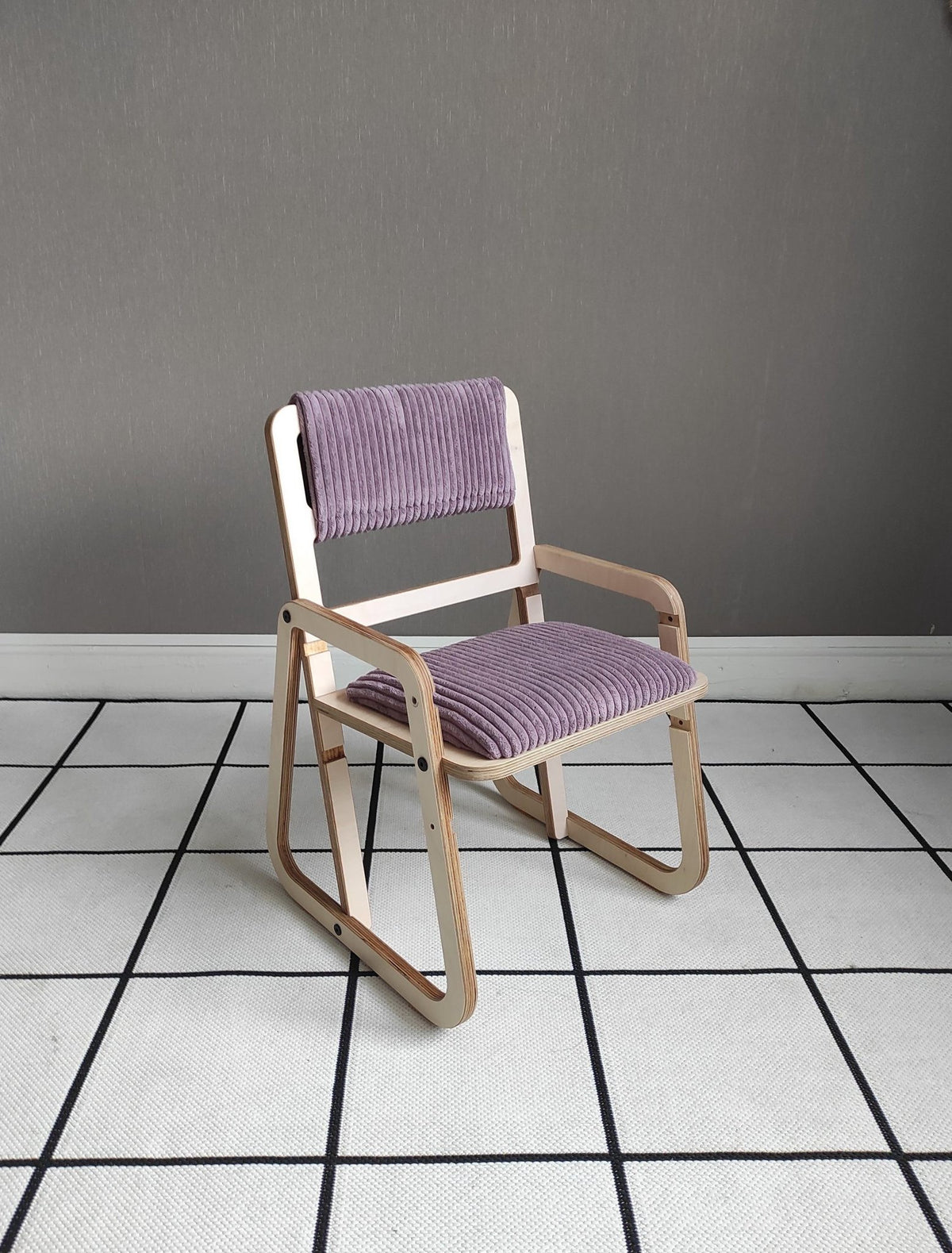 2. Children's chair in cannon pink with wooden frame and armrests on a checkered floor