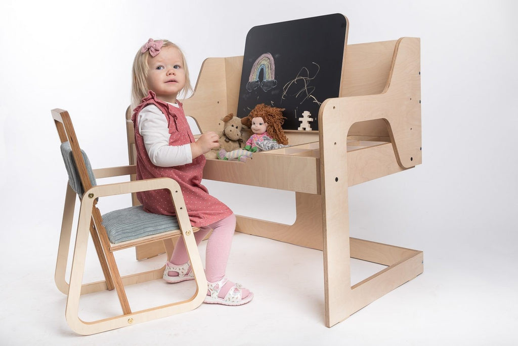 14. Young girl playing at desk while sitting on mint green children's chair on white background