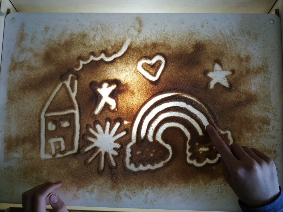 8. Child drawing on LUULA acrylic whiteboard with sand art