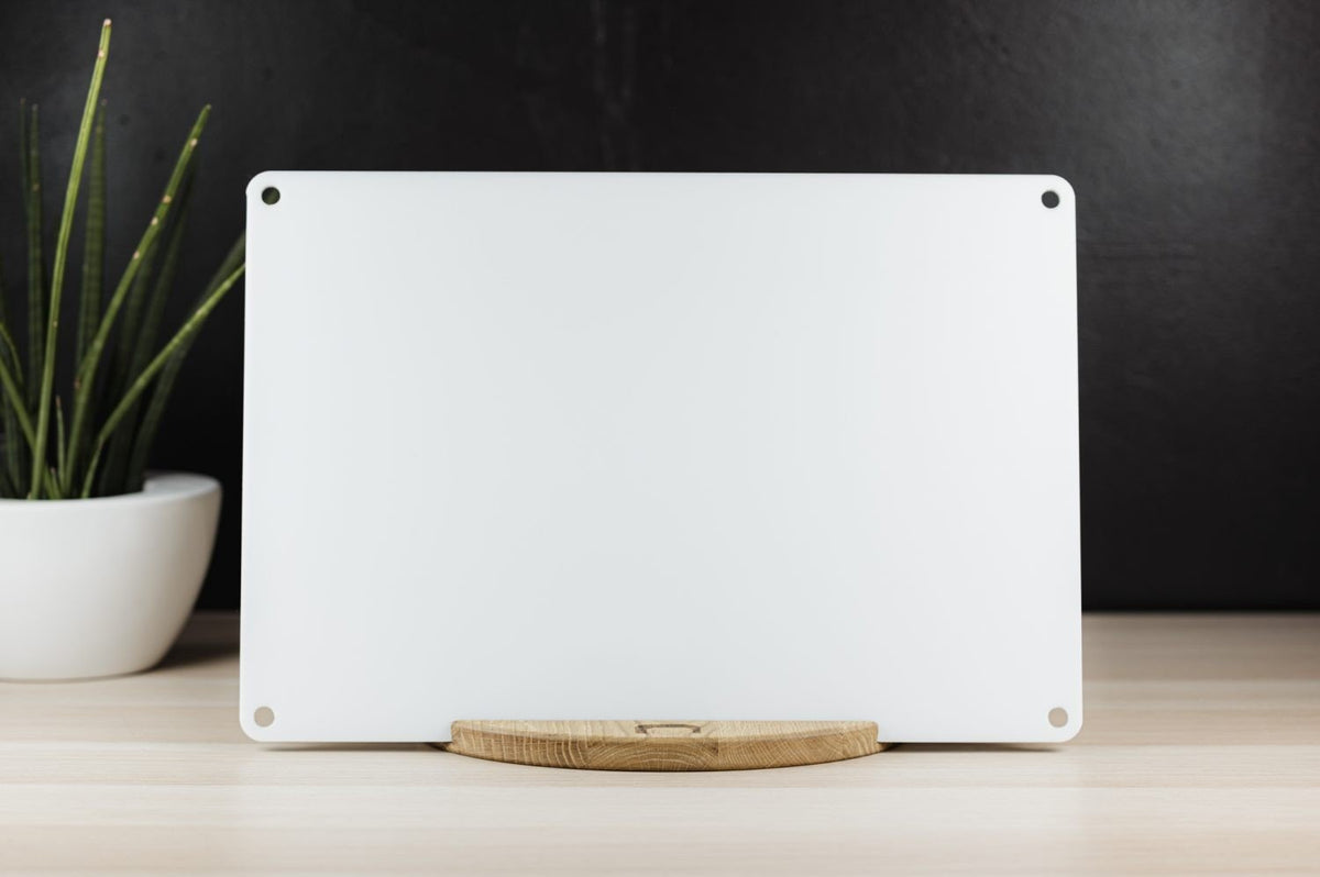 1. LUULA acrylic whiteboard on wooden stand with plant in background on light wood surface