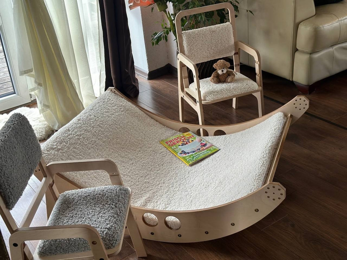 4. Flat lay of Luula children's chairs with grey and beige padding, next to a wooden rocker and a children's book