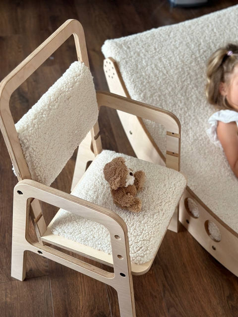 1. Child's adjustable chair in natural wood with soft vanilla lamb padding, placed next to a matching bed on a wooden floor