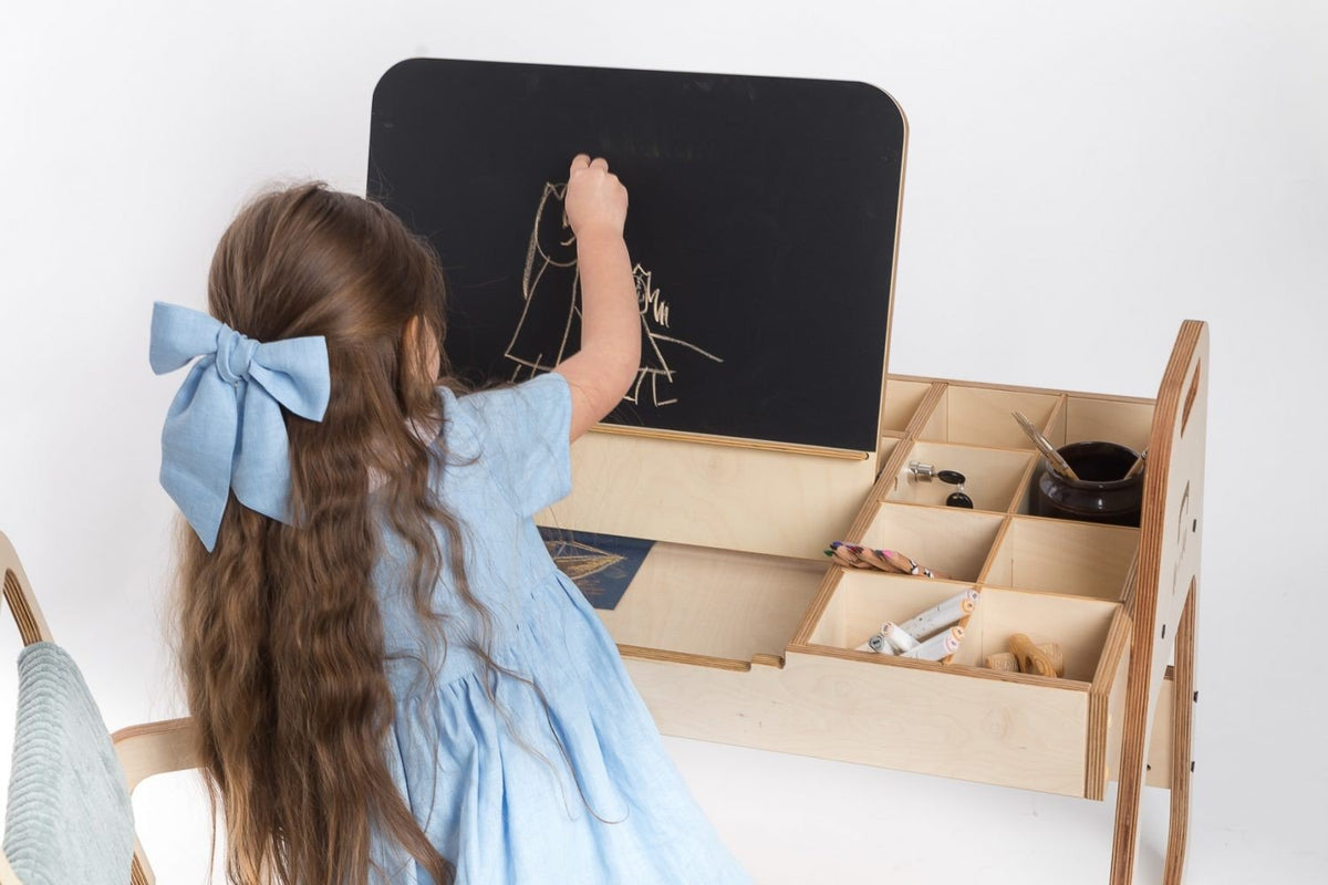 3. Close-up of child drawing on chalkboard at Montessori table