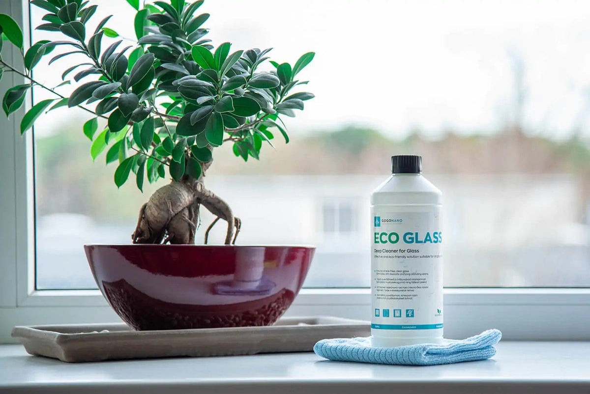 1. GoGoNano EcoGlass cleaner bottle next to plant on windowsill with outdoor view