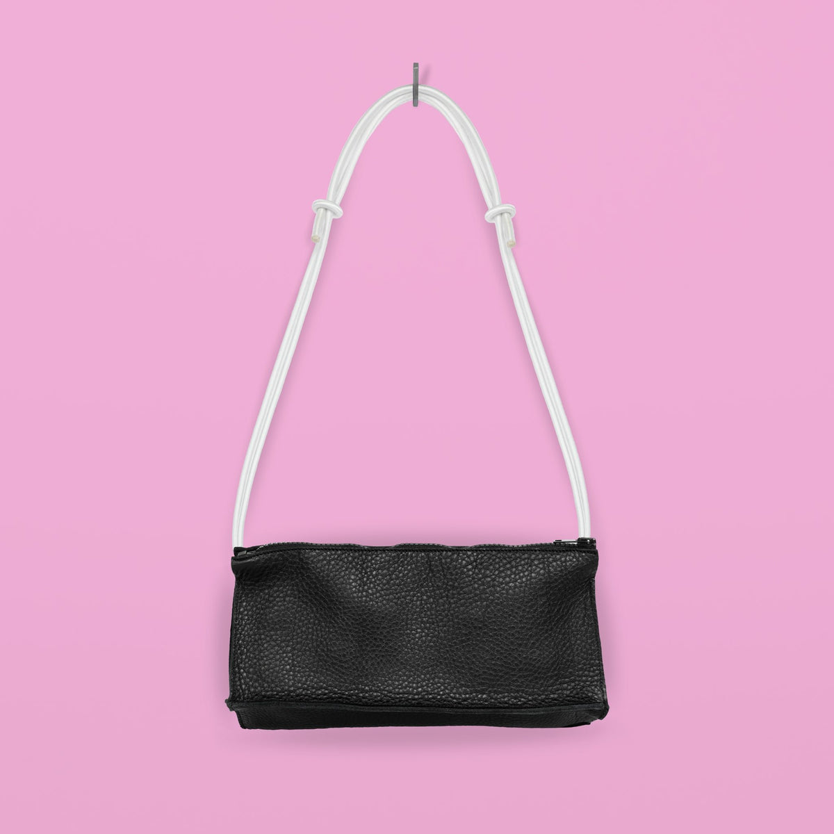 2. Studio shot of Daz Studio handmade leather bum bag in black with white strap, hanging against pink background