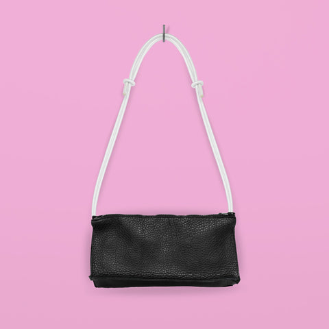 2. Studio shot of Daz Studio handmade leather bum bag in black with white strap, hanging against pink background