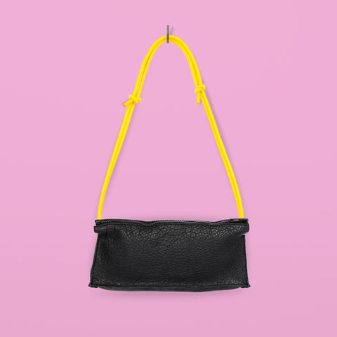 2. Studio image of handmade black leather bum bag with yellow adjustable strap by Daz Studio against pink background