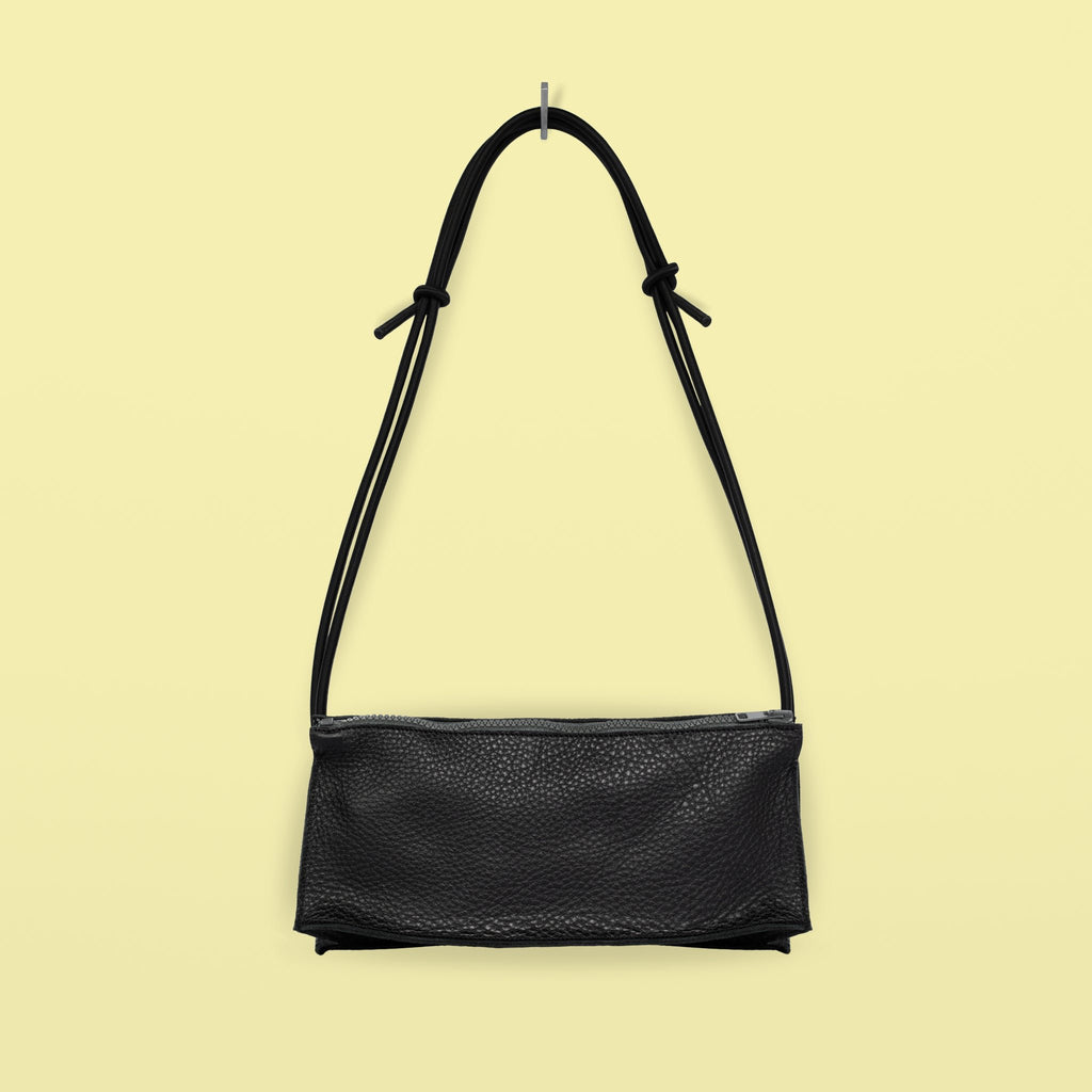 2. Studio shot of Daz Studio handmade black leather bum bag with adjustable strap and grey zipper on yellow background