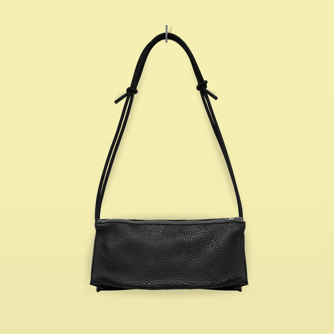 2. Studio shot of Daz Studio handmade black leather bum bag with adjustable strap and grey zipper on yellow background