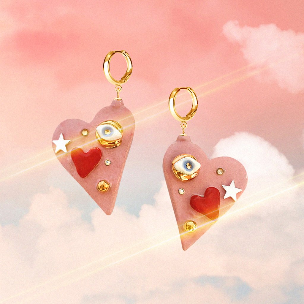 2. SCULP All You Need Is Love earrings with heart and eye design, featuring 24K gold-over sterling silver hoops, shown in artistic setting