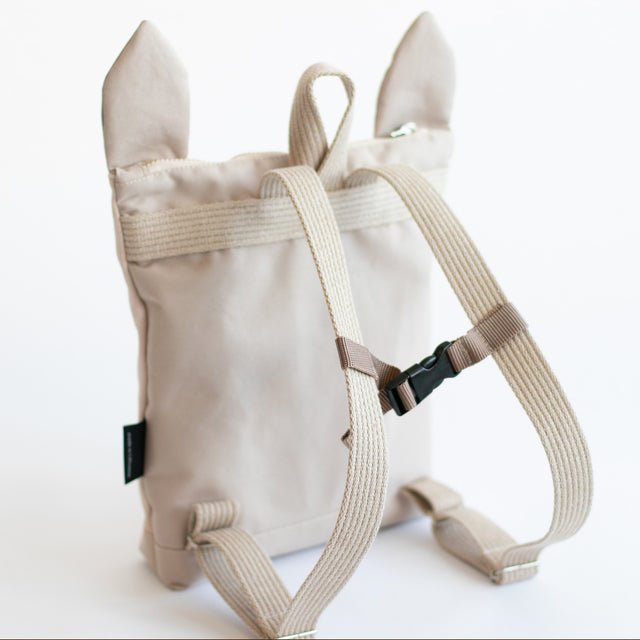 9. Back view of Muni llama backpack in studio, highlighting adjustable straps and beige polyester material