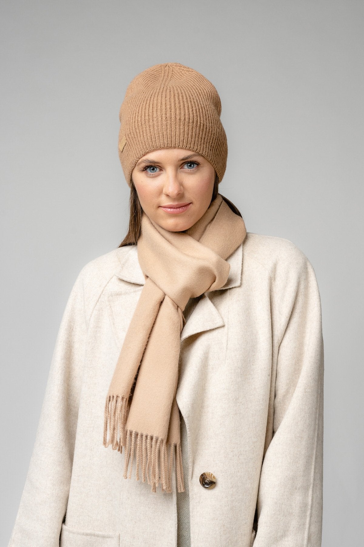 1. Woman wearing beige Alpaka baby alpaca wool scarf and matching hat in studio setting