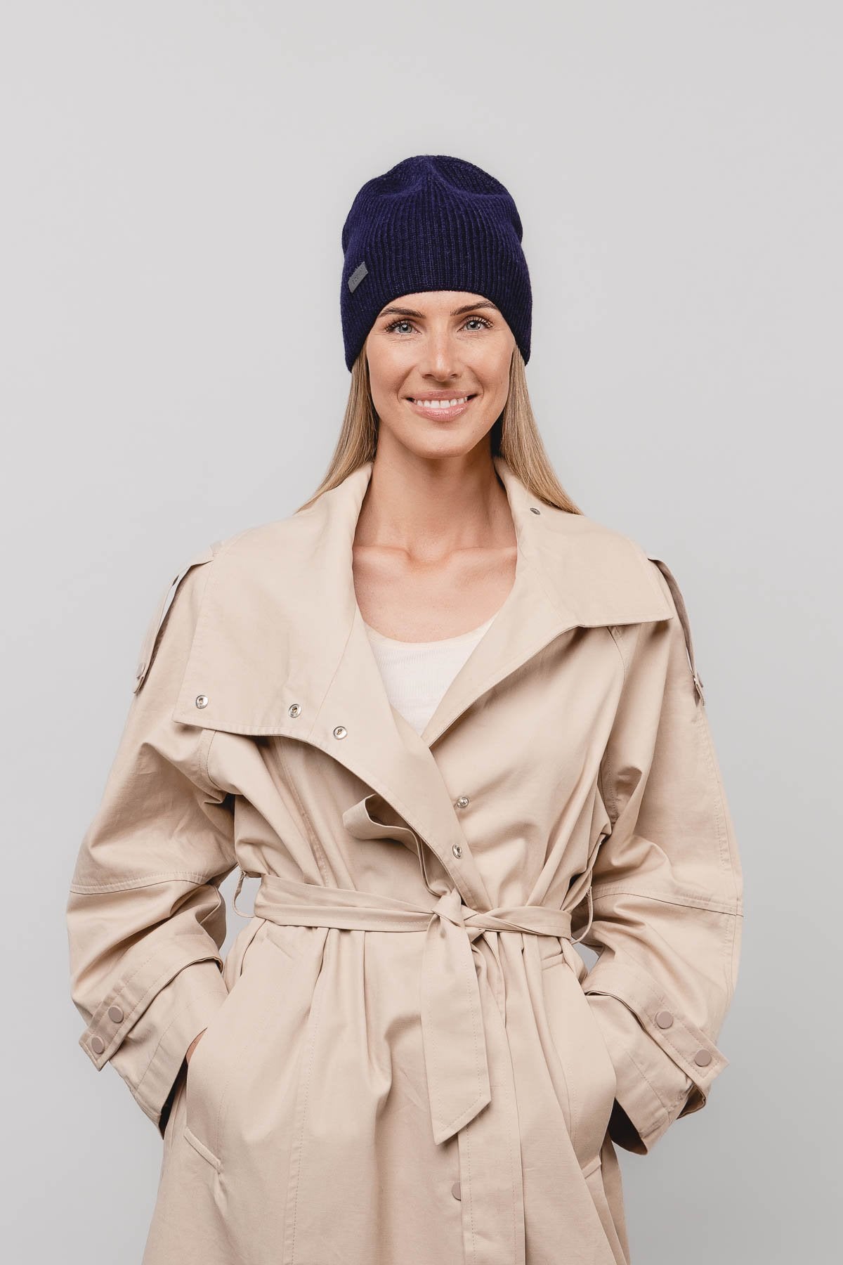 3. Woman wearing navy Alpaka baby alpaca wool fisherman's rib beanie with beige trench coat
