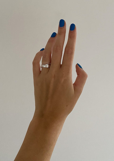 2. Women's hand with blue nails wearing NO MORE Andromeda Ring in sterling silver, shown against a plain background