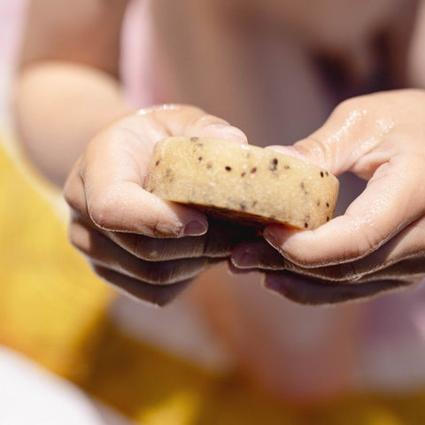 3. Close-up of hands holding Vegan Fox body scrub bar with kiwi seeds, showing texture and size