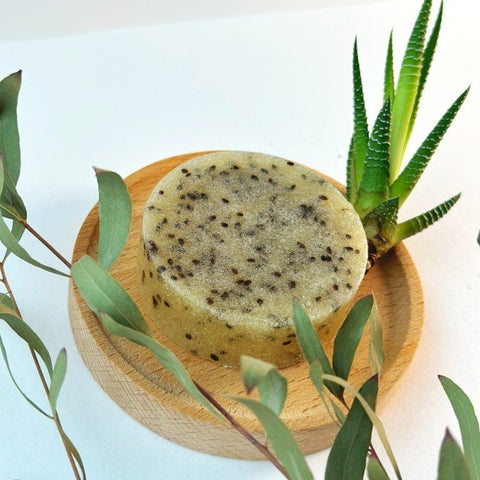 2. Vegan Fox body scrub bar with kiwi seeds on a wooden dish, surrounded by greenery, highlighting natural ingredients