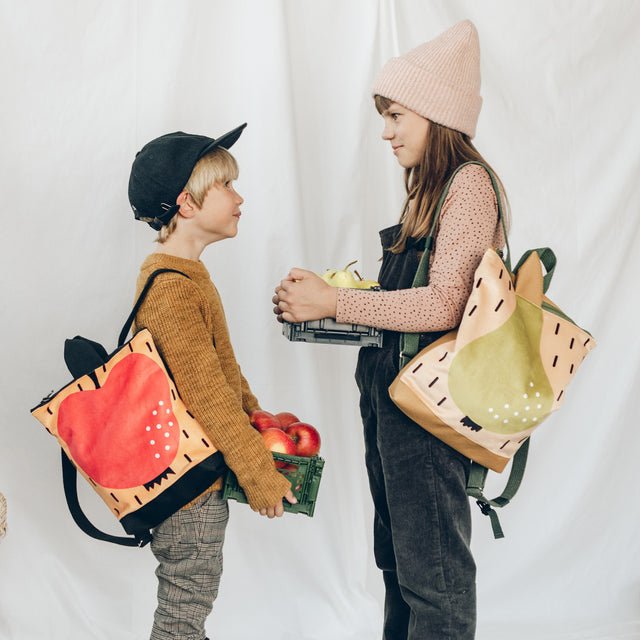 1. Kids wearing Muni apple and pear backpacks, showcasing playful design and functionality