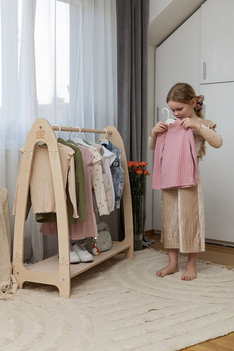1. Girl organizing clothes on natural wood arched clothing rack in stylish room