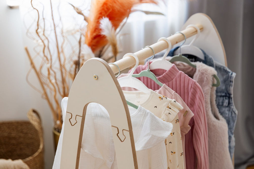 3. Close-up of MeowBaby white arched clothing rack with children's clothes hanging