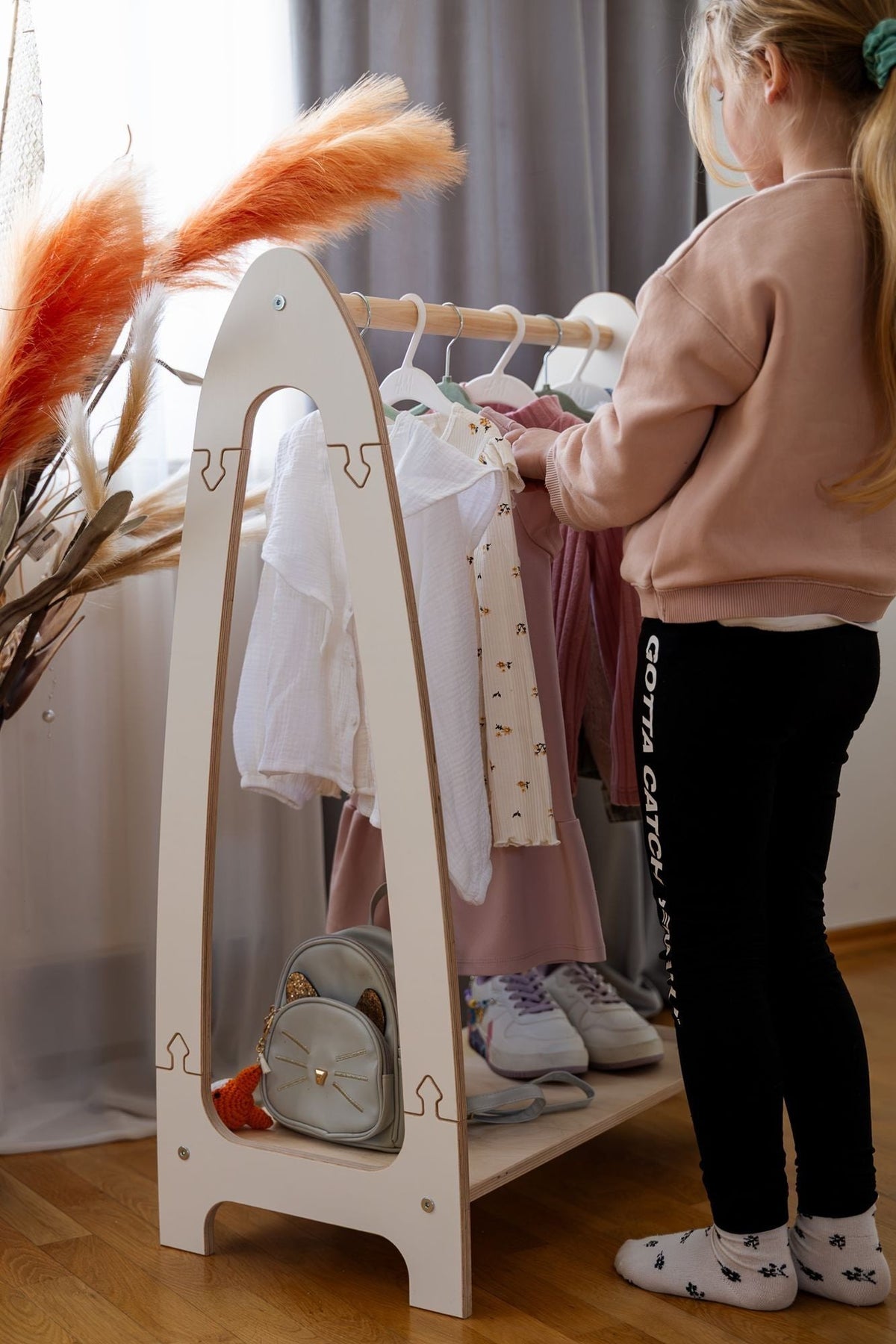 1. Girl organizing clothes on MeowBaby white arched clothing rack in bedroom