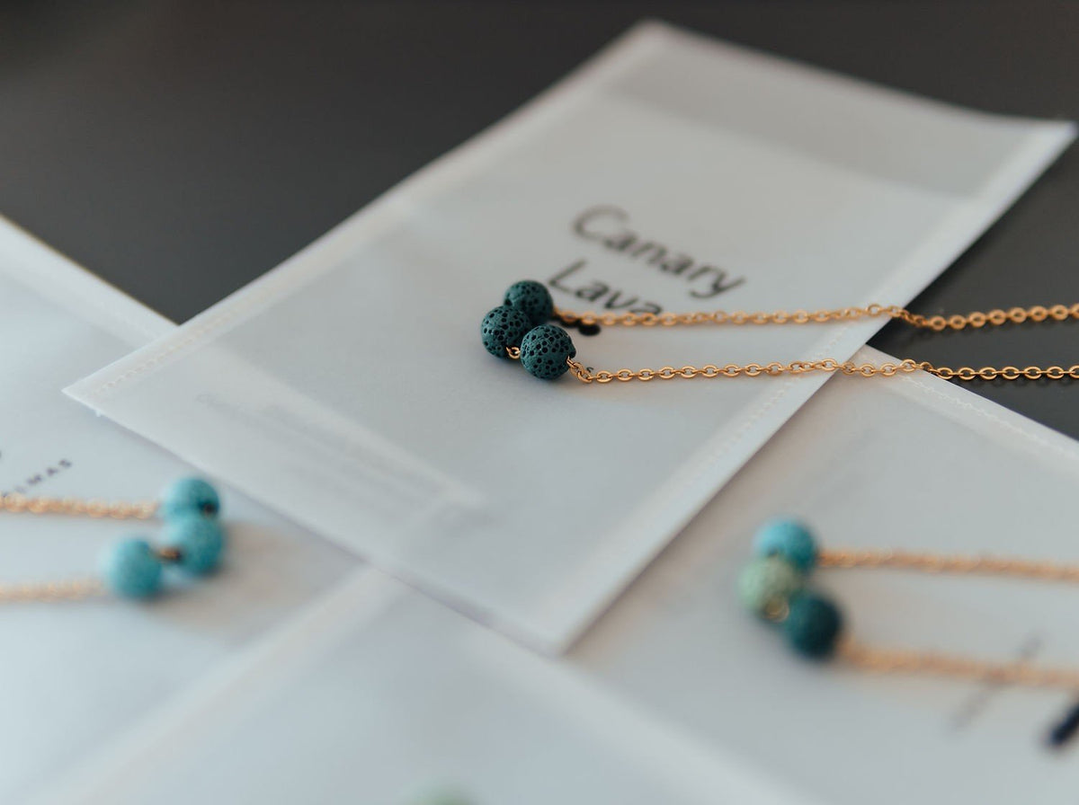 4. Aroma diffuser necklace with dark blue lava beads on silver chain, displayed on branded packaging