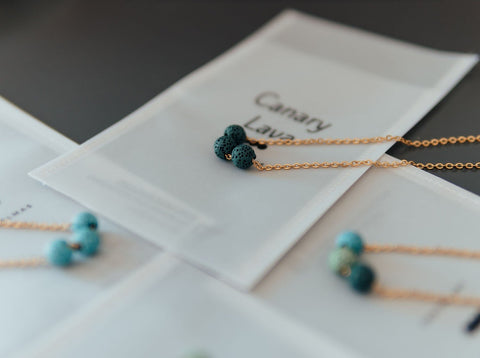 4. Aroma diffuser necklace with dark blue lava beads on silver chain, displayed on branded packaging