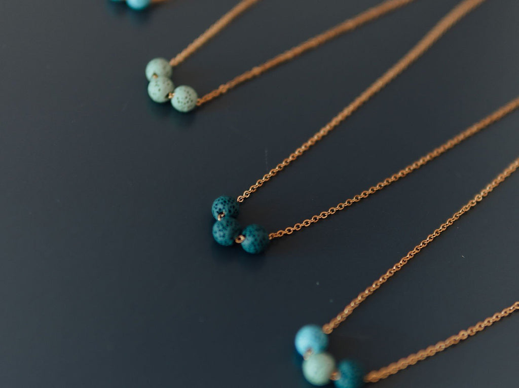 3. Close-up of aroma diffuser necklaces featuring dark blue and turquoise lava beads on silver chains