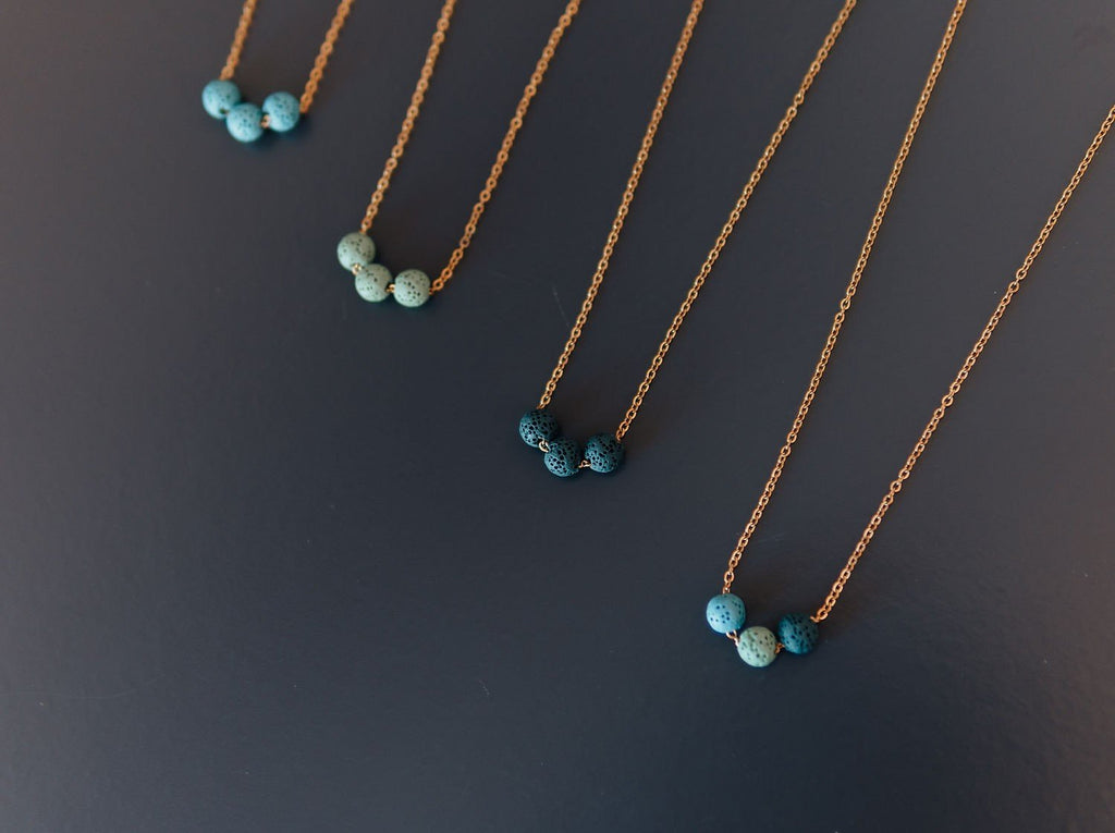 2. Studio shot of aroma diffuser necklaces with dark blue, green, and turquoise lava beads on silver chains