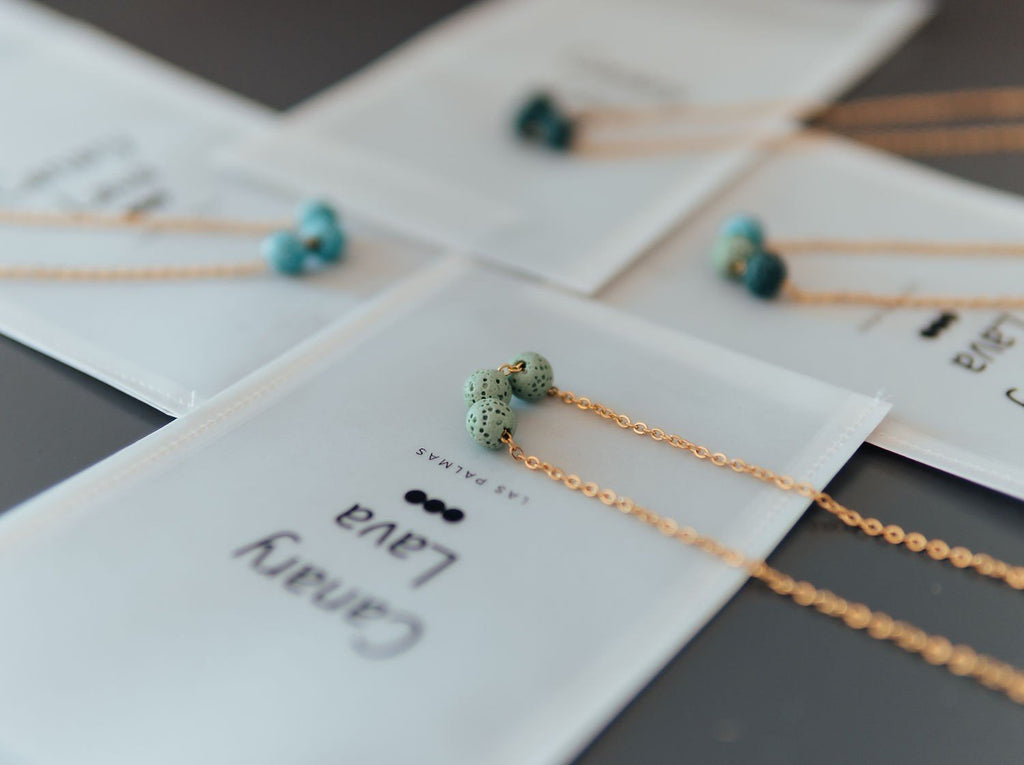 6. Aroma diffuser necklace with green lava beads on silver chain, displayed on branded packaging
