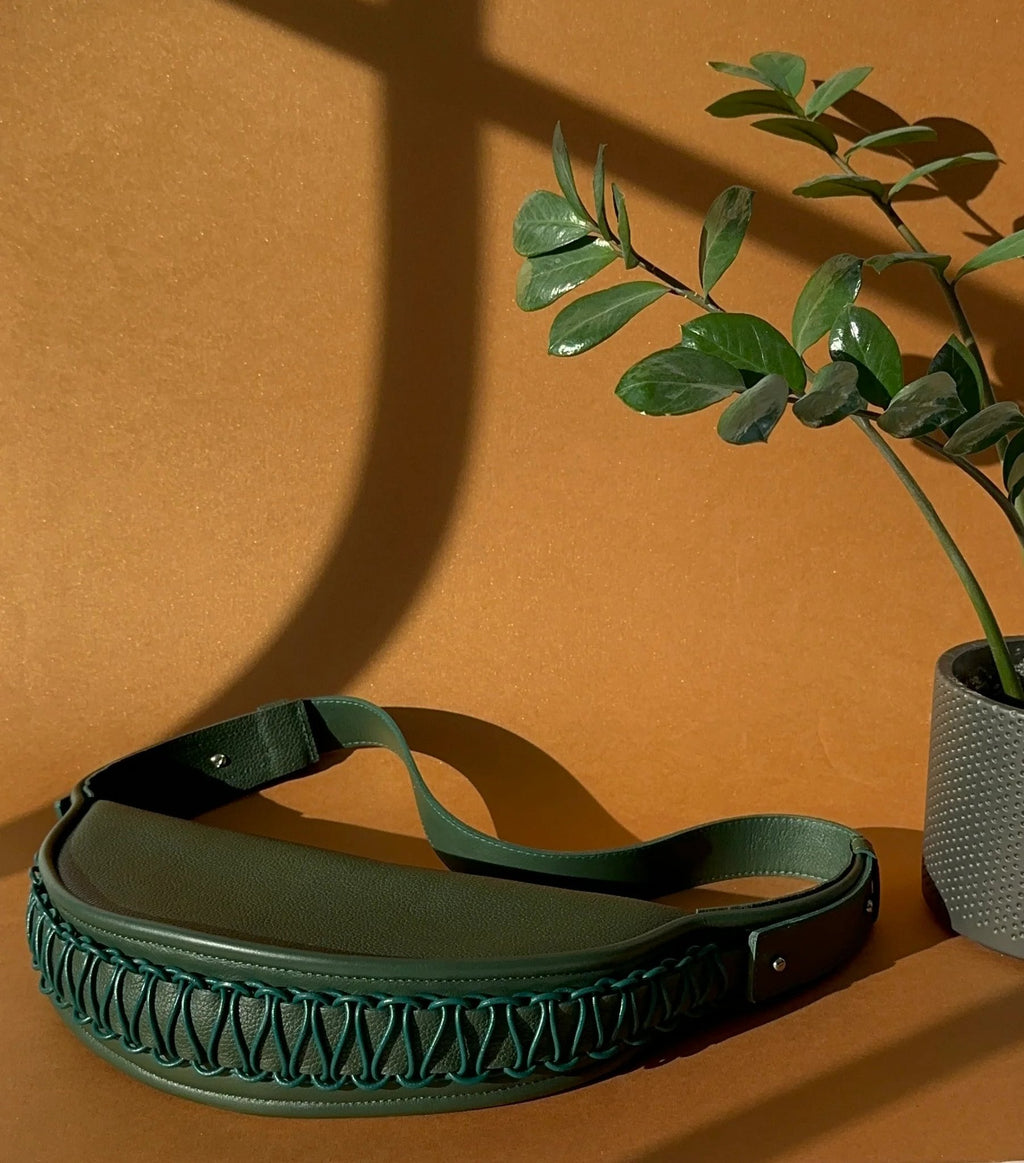 3. Gerda Retter Design Leather Bag Ateena in dark green, styled with a plant, studio setting