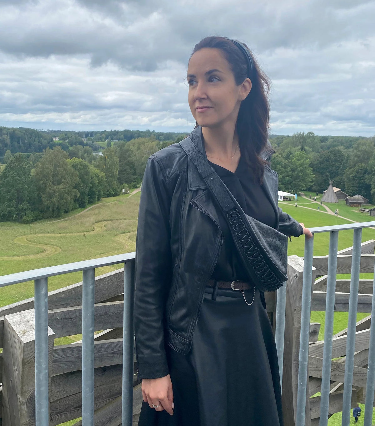 1. Woman wearing Gerda Retter Design Leather Bag Ateena in black as a crossbody, outdoor setting