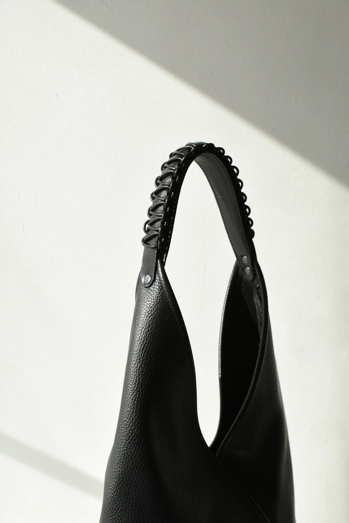 2. Close-up of the handle detail on the black leather tote bag Ateena by Gerda Retter Design, highlighting craftsmanship
