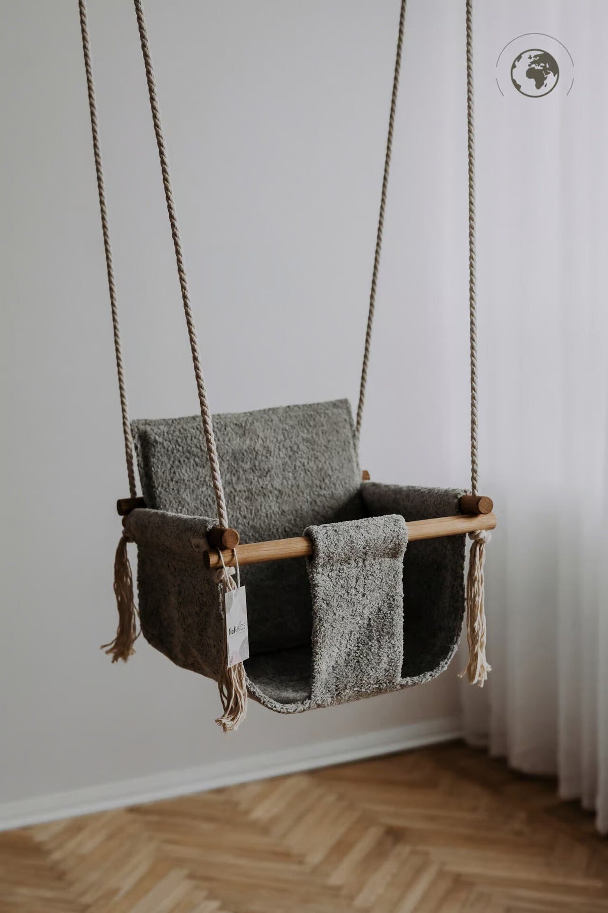 1. Grey bouclé fabric baby swing with oak wood poles hanging in a minimalist room with wooden floor