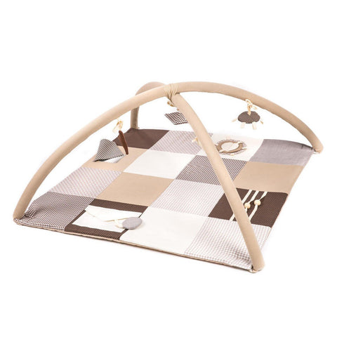 1. Baby lying on Karloova brown activity mat with arches and hanging toys in a living room setting