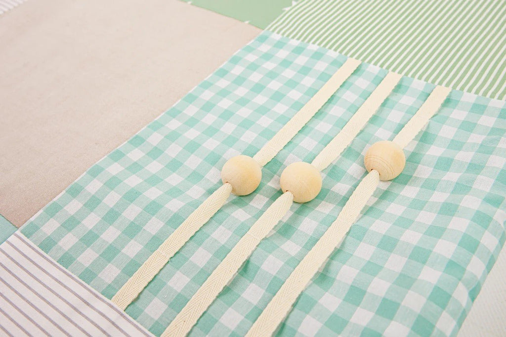 2. Close-up of mint green gingham fabric with wooden buttons on baby activity mat