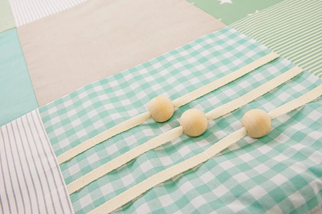 8. Close-up of mint green gingham fabric with wooden buttons on baby activity mat
